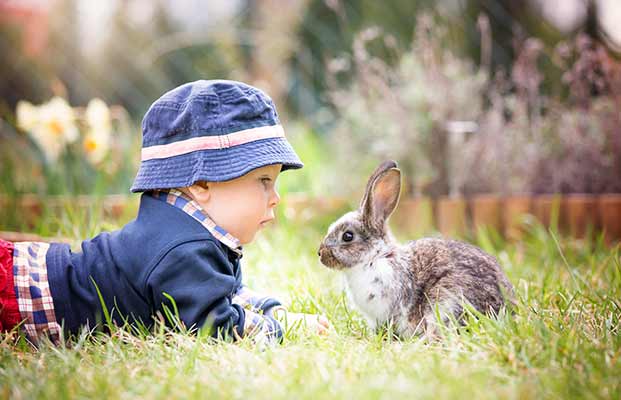 Ein kleiner Junge mit einem kleinen Hasen in einem Garten