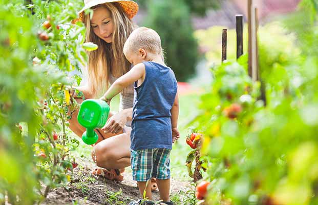 Mutter und Sohn gießen Blumen