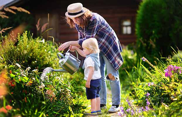 Mutter und Tochter gießen den Garten