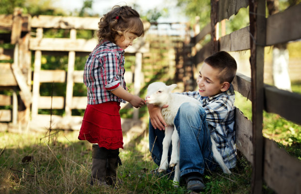 Zwei Kinder unterhalten sich mit einer Ziege